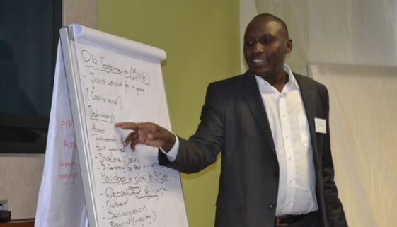 Joel Olloo, a participant from Kenya, gives feedback from his group's breakaway session.